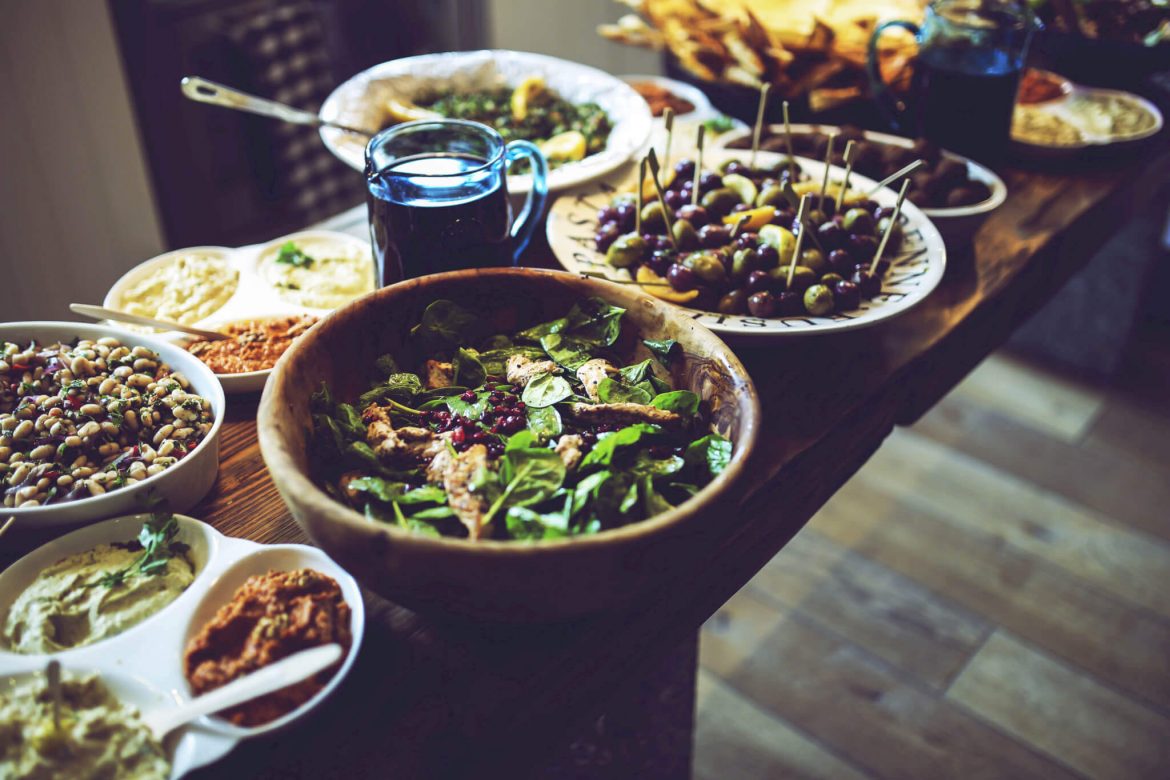 Mesa de almoço com azeitonas, molhos, feijão e vegetais, fontes de proteína