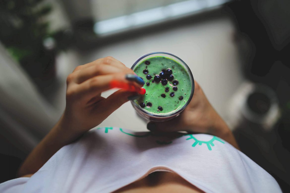 Green Smoothie com mirtilos segurado por uma rapariga de t-shirt